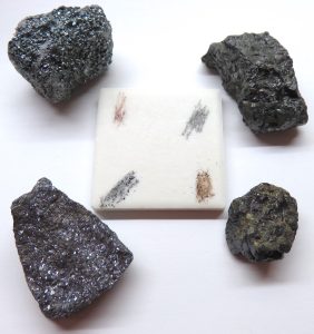 Streaks of hematite (red-brown), magnetite (black), sphalerite (honey-brown), and galena (dark gray) on a streak plate.