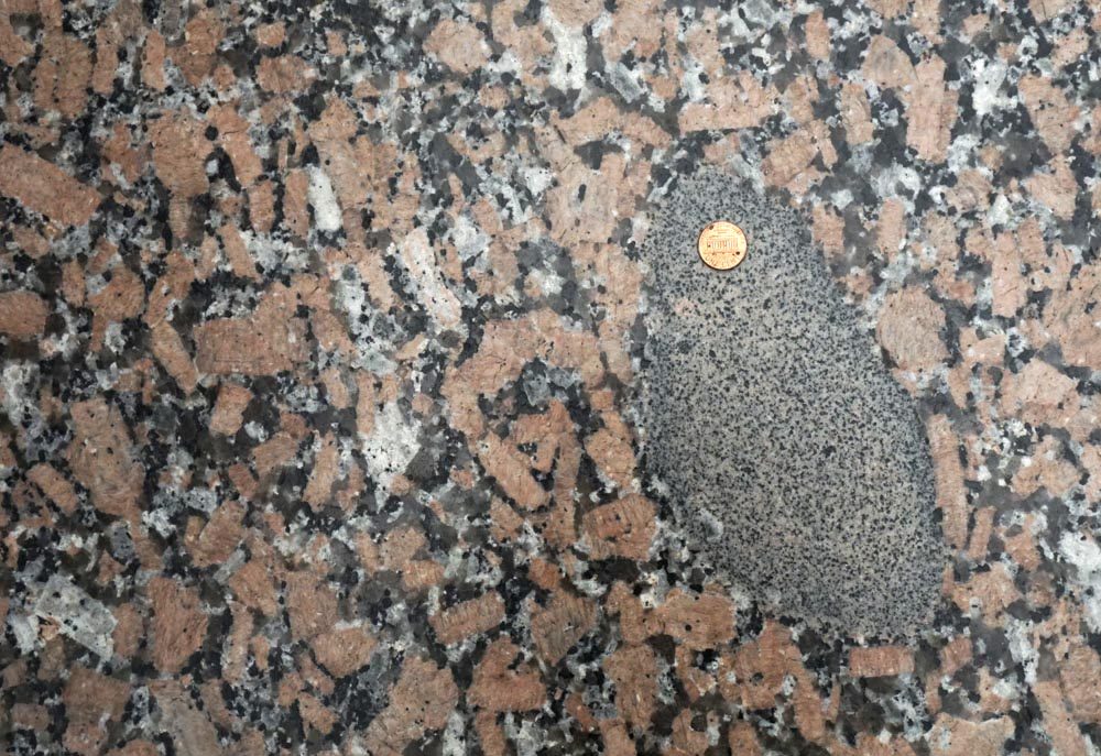 This image shows the principle of inclusions. The dark colored inclusion is older than the surrounding granite.