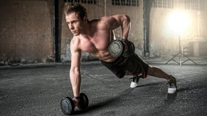 Man without a shirt performs a renegade row in a warehouse-looking building